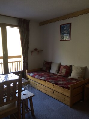 A cozy room with a wooden bed, a small table, and chairs. - Les Ménuires "quartier les Bruyères" Pieds des Pistes+parking (Les Menuires)