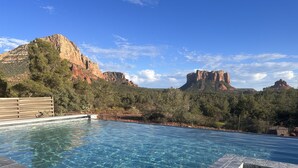 A clear pool with a view of red rock formations and trees in the background. - Hiker's Paradise infinity pool, trail access to Chapel of Holy Cross and Mystic (Sedona)