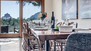 A dining area with a long table set for six, wooden chairs, a vase with flowers, and a bottle of wine. - Hiker's Paradise infinity pool, trail access to Chapel of Holy Cross and Mystic (Sedona)
