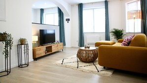 A modern living room with a sofa, TV, and decorative plants.