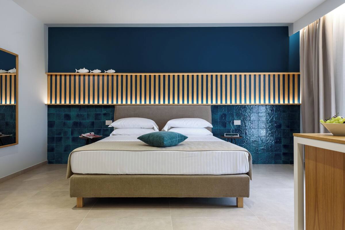 A modern bedroom with a large bed, a wooden headboard, and a blue accent wall.
