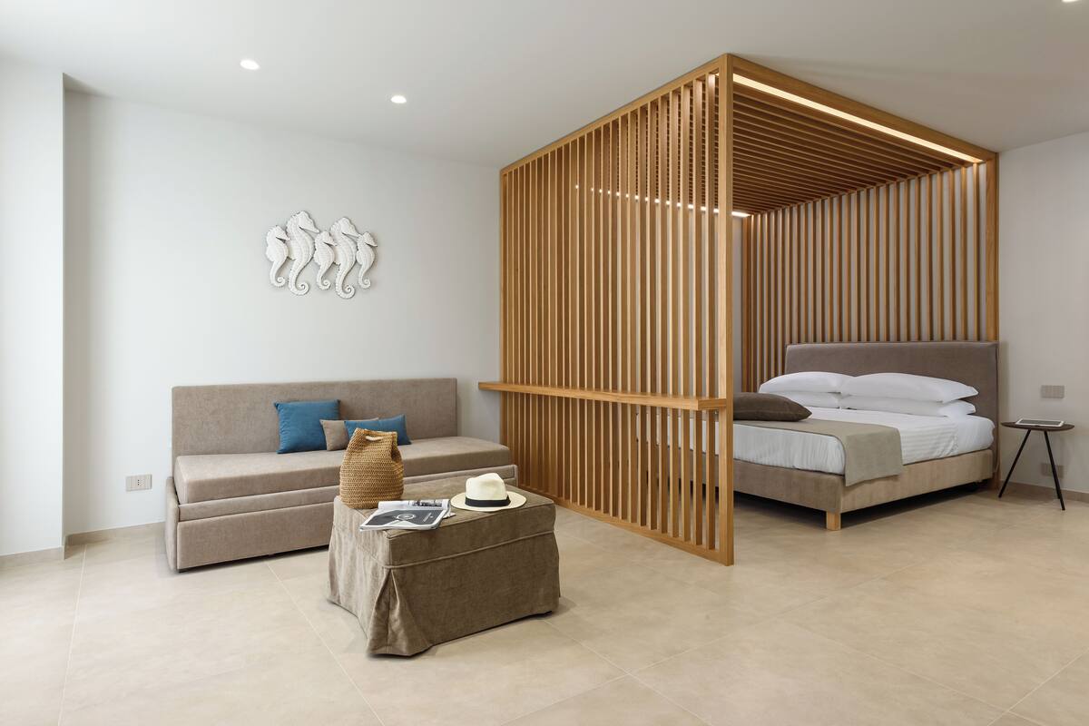 A modern bedroom with a bed, a sofa, a coffee table, and a decorative wall piece.