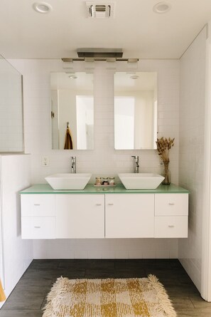 Une salle de bain moderne avec deux lavabos, un grand miroir et un plancher en bois foncé.