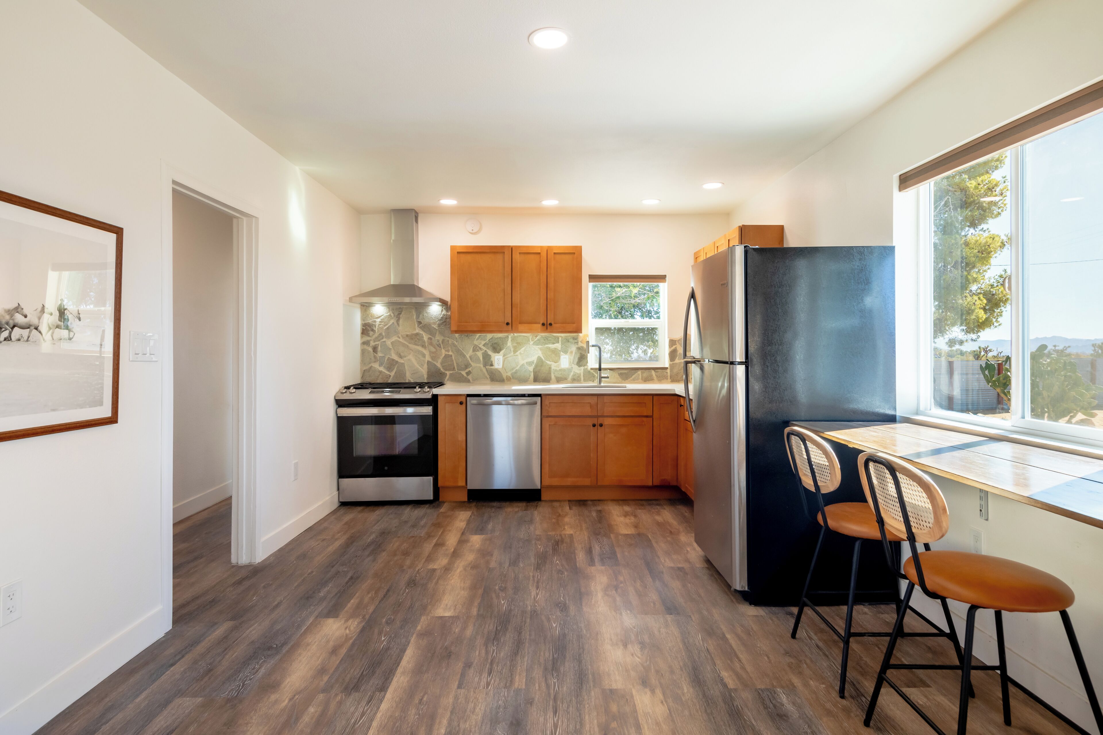 A modern kitchen with wooden cabinets, a stainless steel refrigerator, and a built-in oven.