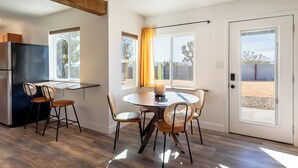 A modern kitchen with a built-in refrigerator, wooden flooring, and a dining area with a round table and four chairs. - New! The Aberdeen House - Private Acreage + Joshua Trees + Hot Tub! (Yucca Valley)