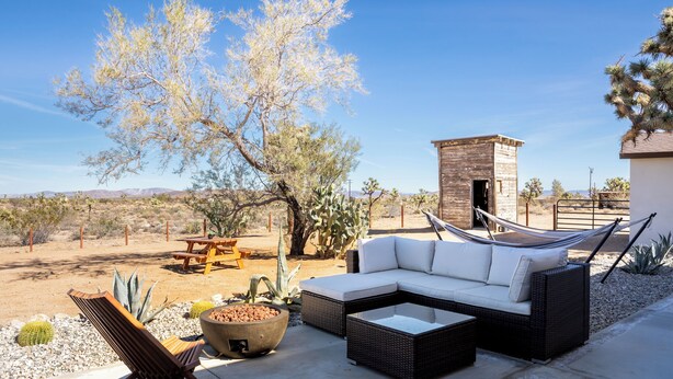 A patio with a sectional sofa, a hammock, and a fire pit. - New! The Aberdeen House - Private Acreage + Joshua Trees + Hot Tub! (Yucca Valley)