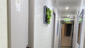 Un couloir avec les portes numérotées 4 et 5, un panneau de signalisation verte indiquant la sortie, et une plante accrochée au mur.