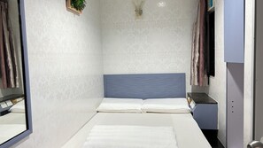 A modern bathroom with a large mirror, a bed with white bedding, and a blue headboard. - Ming Shing Guesthouse (Hong Kong)