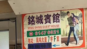 Une enseigne indiquant le nom de la maison d’hôtes Ming Shing, avec un numéro de téléphone et l’emplacement des chambres.
