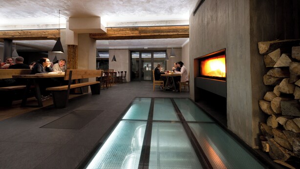 A restaurant with a glass floor, wooden beams, and a fireplace. - Hotel Bohemia (Zelezna Ruda)