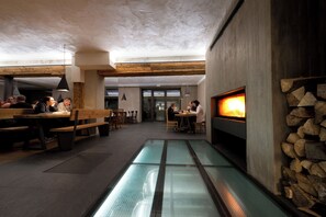 Un restaurante con suelo de vidrio, vigas de madera y chimenea.
