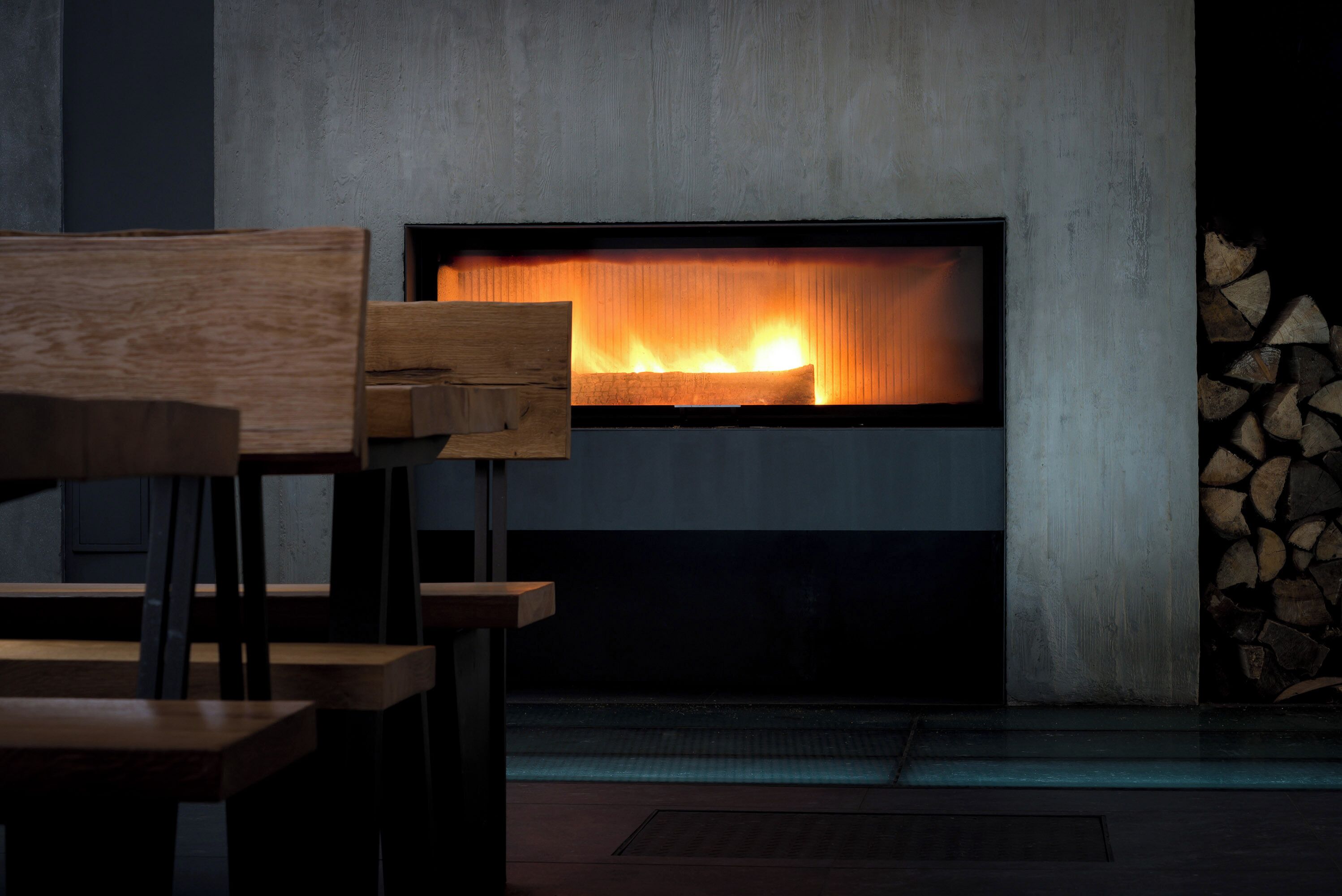 Ein modernes Interieur mit Kamin, Holzmöbeln und einem Holzstapel.
