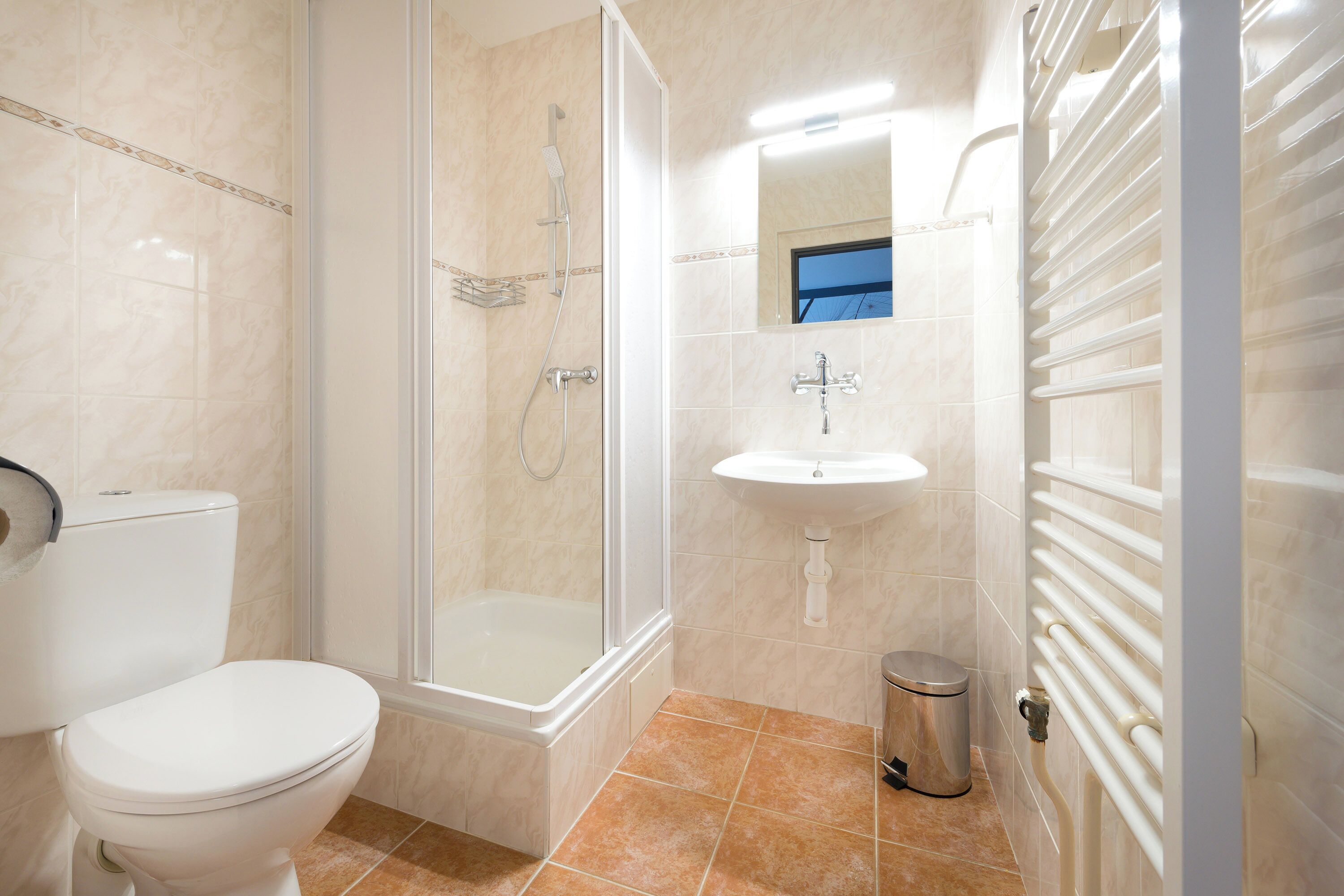 Un baño con inodoro, ducha, lavabo y radiador.