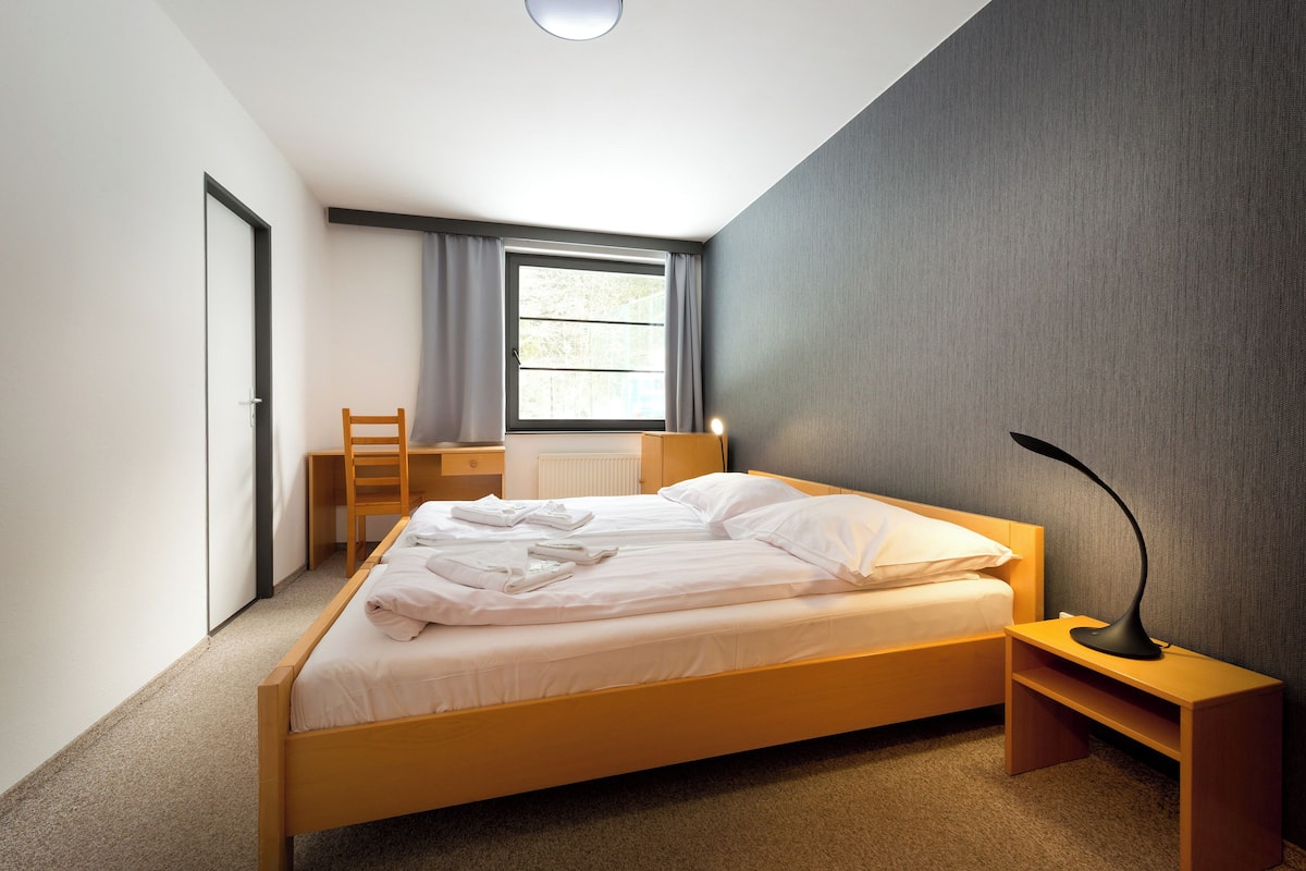 Une chambre à coucher moderne avec un lit en bois, un bureau et une chaise.