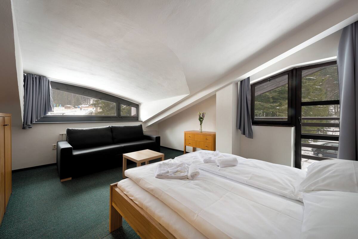 Une chambre d’hôtel moderne équipée d’un lit, d’un canapé, d’une petite table et d’une table de chevet.