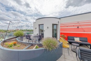 Eine Dachterrasse mit Sitzgelegenheit, einem Blumenbeet und einer roten Wand.