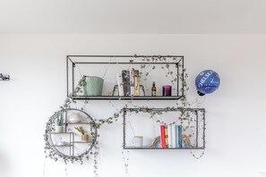 Deux étagères fixées au mur, sur lesquelles on trouve des livres, des objets décoratifs et une sphère bleue.