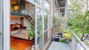 A modern interior with a sofa, a dining table, and a staircase leading to an upper level. - Bright and Airy 2BD Flat in Haggerston (London)