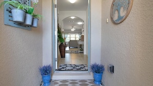 A hallway with a patterned rug leading to a room with a ceiling fan and a door. - South Gulf Cove 4BR/2BA Heated Pool ,15 mins to the GULF (Port Charlotte)