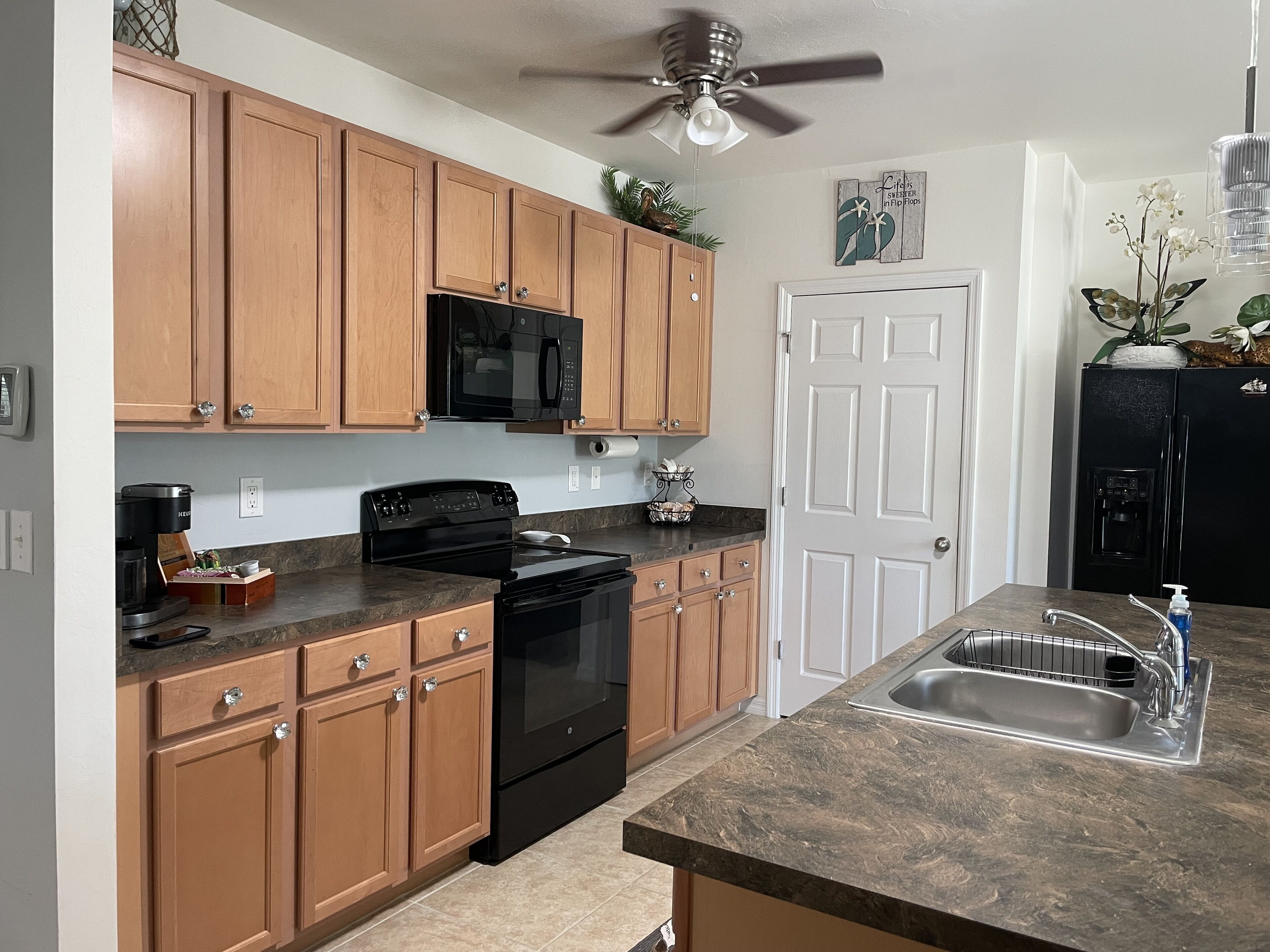 A kitchen with wooden cabinets, a black stove, a microwave, and a refrigerator.