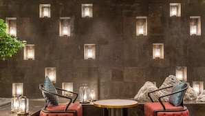 A seating area with two cushioned chairs and a round table, set against a wall with recessed lighting. - Rezen Dong Hotel (Shanghai)