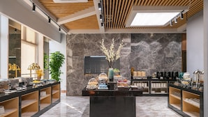 A modern breakfast area with marble flooring, a central serving counter, and a decorative plant. - Rezen Dong Hotel (Shanghai)