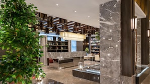 A modern lobby with marble flooring, a central seating area, and a large plant. - Rezen Dong Hotel (Shanghai)