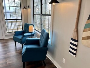 Relax in a serene space with a pair of armchairs near a large window offering a view of the surrounding trees.