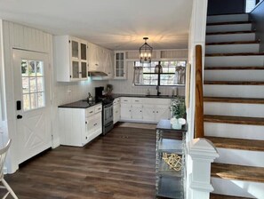 Kitchen with oven, stainless steel sink, and wooden staircase.