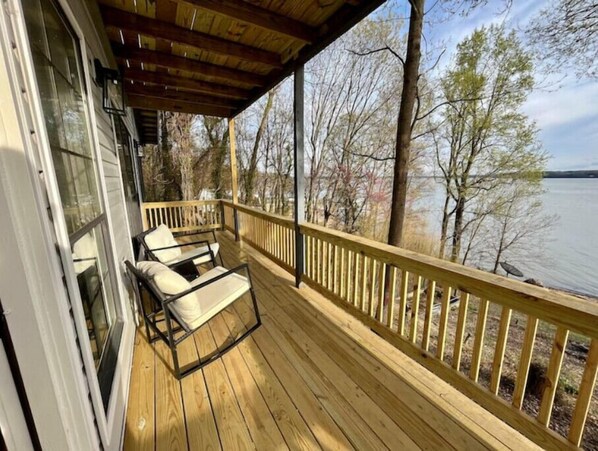 Enjoy a serene view from this deck overlooking the water, perfect for relaxing with a pair of comfortable chairs.