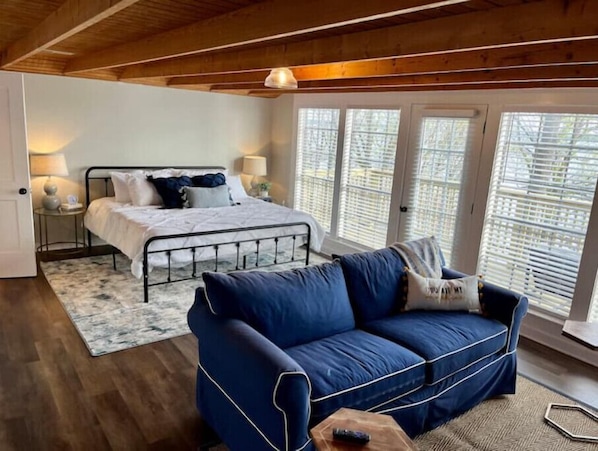 A bedroom with a bed, a blue sofa, and a window with blinds.
