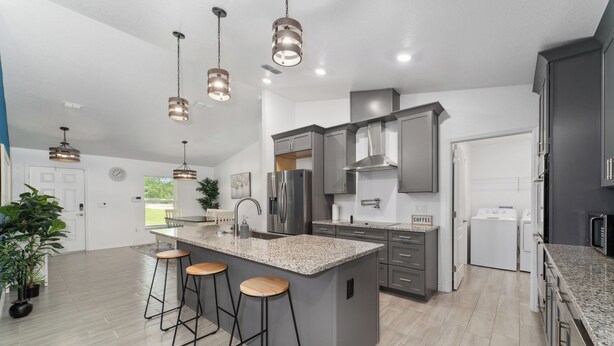 A modern kitchen with a central island, bar stools, stainless steel appliances, and pendant lighting. - Country Style Oasis! With cleared trails for walking or exploring (Polk City)