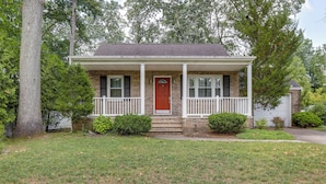 A two-story brick house with a red front door, white porch columns, and a small front yard with grass and shrubs. - Charming Monroe Township Home - 13 Mi to RU! (Monroe Township)
