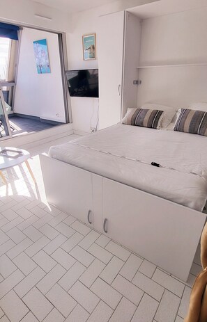Une chambre d’hôtel équipée d’un lit, d’un téléviseur fixé au mur, d’une petite table et d’une porte coulissante donnant sur un espace extérieur.