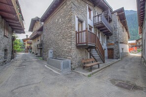 Una calle estrecha con edificios de piedra, balcones de madera y un banco.