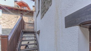 Een trap die leidt naar een houten balkon met stenen muren.