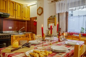 Une table à manger dressée avec des assiettes, des verres et des bougies, entourée de chaises en bois.