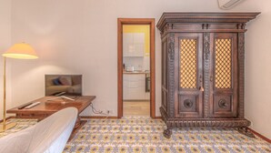 Ein Zimmer mit einem Bett, einem Schreibtisch mit Lampe, einem Fernseher und einem Holzschrank.