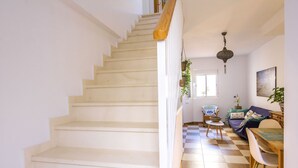 Eine Treppe führt zu einem Wohnbereich mit kariertem Boden, einem Sofa und einem Esstisch.