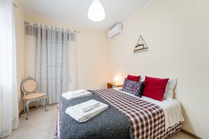 Camera d'albergo con un letto, una sedia, un comodino e un condizionatore d'aria a parete.