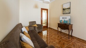 A furnished living room with a sofa set, a wooden side table, and a painting on the wall.