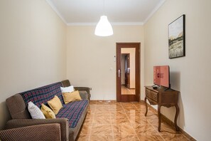 Un soggiorno con divano, un tavolino in legno, un quadro e una porta che dà su un'altra stanza.