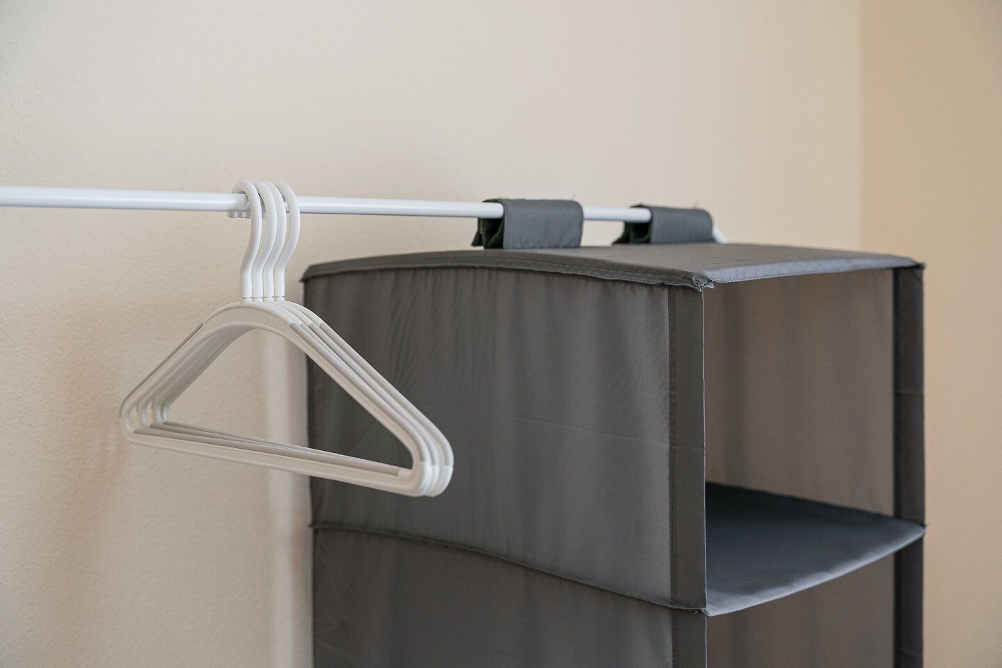 A grey storage unit with a hanging garment rack attached to a metal rod.