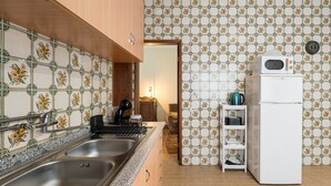 A kitchen with a double sink, a stove, a white refrigerator, and a tiled backsplash with floral patterns.