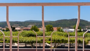 A metal railing with a view of vineyards and distant hills.
