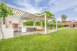 Eine moderne Außenpatio mit integriertem Grill, Sitzbereich und einer Pergola.