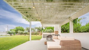 An outdoor patio with a covered seating area, a dining table, and a grill. - Refreshing poolside escape in Ponte de Sor (Portalegre)