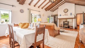 A cozy dining area with a wooden table, chairs, and a woven basket. - Refreshing poolside escape in Ponte de Sor (Portalegre)