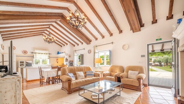 A spacious living area with a high ceiling, wooden beams, and a glass coffee table. - Refreshing poolside escape in Ponte de Sor (Portalegre)