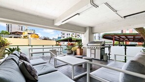 Eine Außenpatio-Terrasse mit Grill, Sitzgelegenheiten und Topfpflanzen.